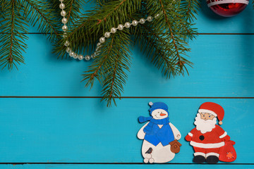 Handmade wooden Christmas tree decorations (Santa, Angel, Christmas tree, snowman) on a blue vintage table with Christmas tree. With blank and free space.