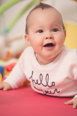 Wall Mural - Eight months old baby girl playing with colorful toys on a floor