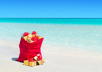 Canvas Print - Christmas sack full of wrapped gift boxes at tropical beach