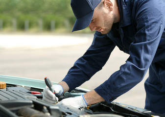 Sticker - Mechanic in uniform repairing car in open hood, close up