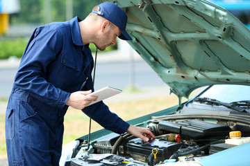 Sticker - Mechanic standing in front of an open car hood with the tablet