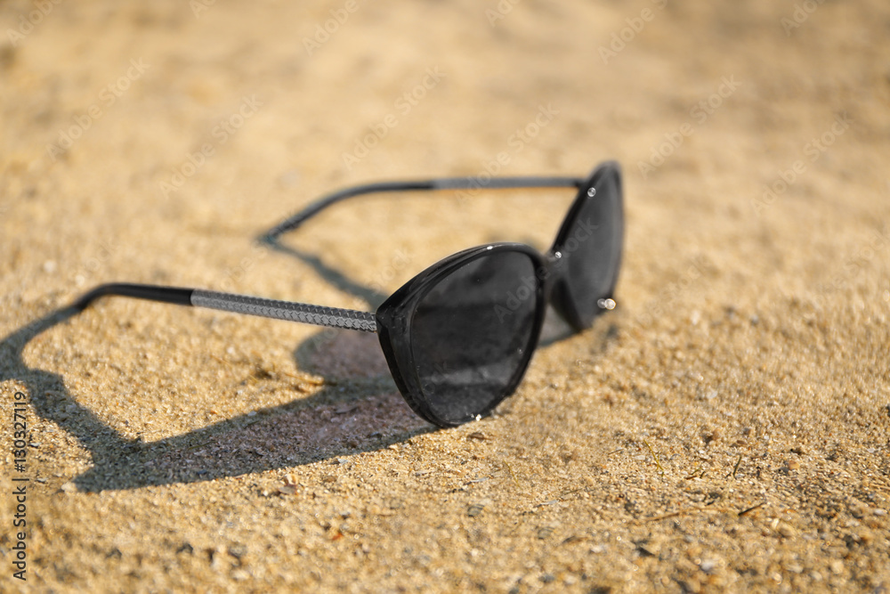 Sunglasses on sand beach, close up view