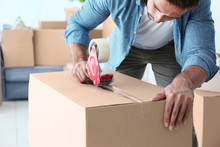 House Moving Concept. Closeup Of Man Packing Cardboard Box