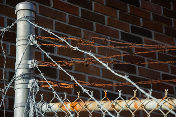 Barb wire fence in front of a brick prison