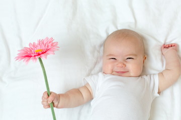 happy newborn baby girl playing with a flower