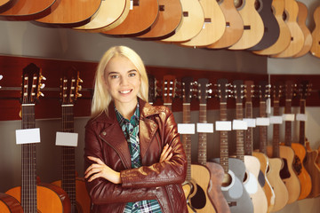 Wall Mural - Female saleswoman with guitars in shop