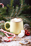 Fototapeta Desenie - mug with hot chocolate, christmas tree, tangerines, peppermint stick and marshmallow on a snow wooden background with falling snow. Dark photo. Vertical shot