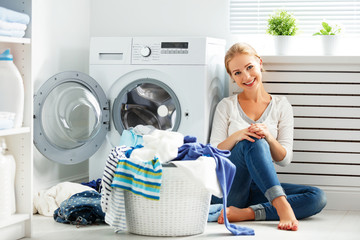 happy woman housewife in the laundry room near the washing machi