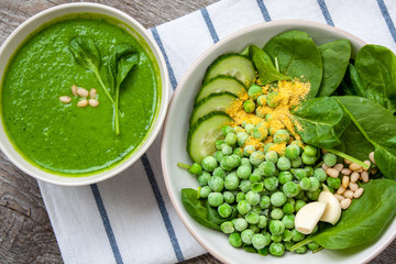 Wall Mural - Green peas spinach basil pesto and Ingredients in a white bowl on a wooden background. Love for a healthy raw food concept.