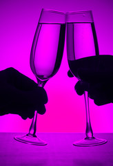 Wall Mural - silhouette of hands with two glasses of champagne on the colored