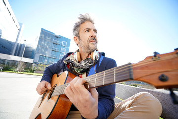 Wall Mural - Mature trendy guy playing the guitar in the street