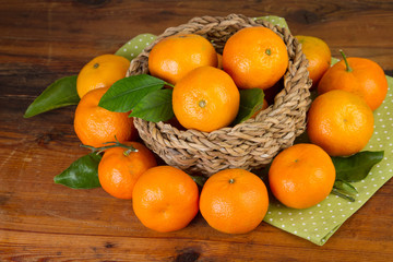 Wall Mural - tangerine basket full with green napkin on old wooden background