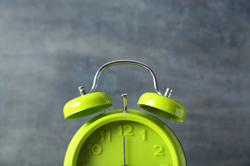 Green alarm clock on a grey wooden table