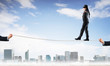 © adam121 - Business concept of risk support and assistance with man balancing on rope