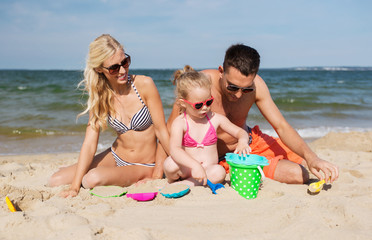 Canvas Print - happy family playing with sand toys on beach