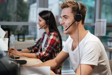 Wall Mural - Side view of Coworkers sit by the table in headphones