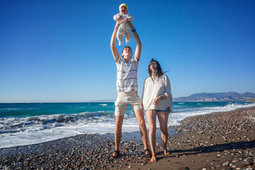 Young happy couple with a baby on a beautiful seashore. Family l