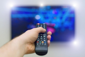 Male hand holding TV remote control.