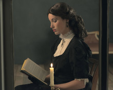Retro Victorian Girl Reading Book By Candlelight Behind Window.