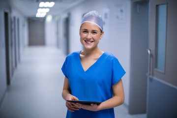Poster - Female nurse using digital tablet in corridor
