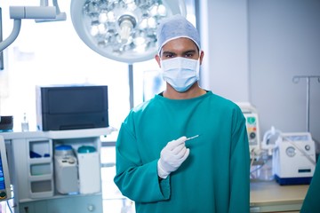 Poster - Male surgeon standing with surgical tool in operation theater