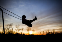 Silhouette Girl Playing On Swing Against Sky During Sunset