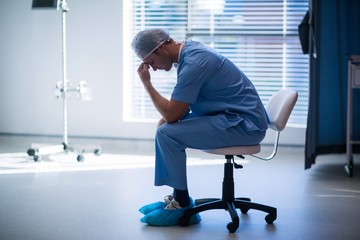 Poster - Tensed male nurse sitting in corridor
