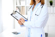 © rogerphoto - Close up of  female doctor  writing a medical prescription at clipboard while standing