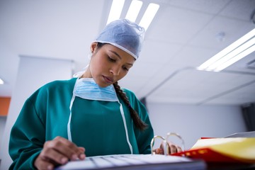 Poster - Female surgeon reading reports in operation theater