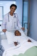© WavebreakMediaMicro - Female doctor standing with patient lying on bed