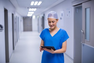 Poster - Female nurse using digital tablet in corridor