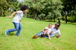 © twinsterphoto - Two kids chasing and playing together while dad caught a boy in park