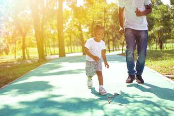 African American boy walking and playing with dad in green park