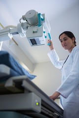 Female doctor adjusting x-ray machine while examining