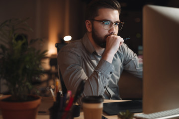 Serious bearded web designer looking at computer.