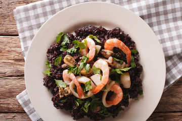 Risotto of black rice with seafood close up on a plate. Horizontal top view