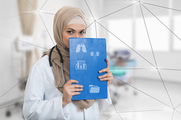 Wall Mural - portrait of worried muslim female Medical doctor holding paperclip at hospital