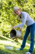 Senior woman putting potatoes in bowl from bucket in garden