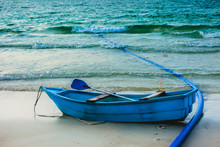  A Small Blue Rowing Boat Parked On The Beach.