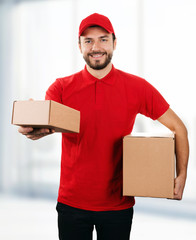 Wall Mural - delivery service - young smiling deliveryman with cardboard boxes