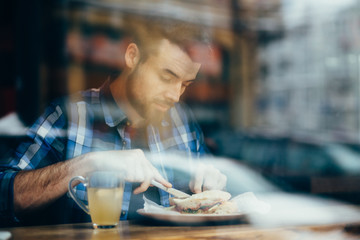 Handsome young man having lunch in elegant restaurant alone