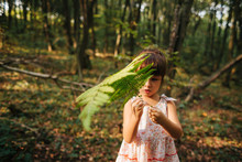 Little Girl Standing In The Forest With Ferns