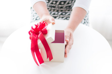 Poster - Gift box with hands woman opening the box on white table
