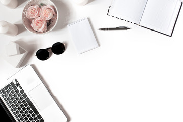 Minimalistic modern workspace with laptop keyboard, vintage tray with roses, notebook, sunglasses in flat lay style. White background. Top view.