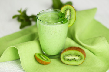 Fototapete - Glass of kiwi smoothie on green napkin