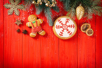 Wall Mural - Composition of tasty gingerbread cookies and Christmas decor on red wooden background