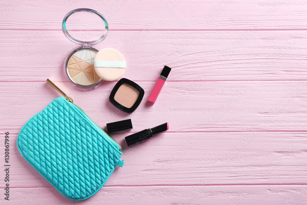 Turquoise make up bag and decorative cosmetics on pink wooden background