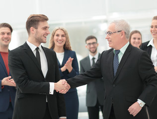 Poster - Two cheerful business people shaking hands while their colleague