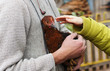 A man holds a chicken on hand. Child pulls hand. A hen.