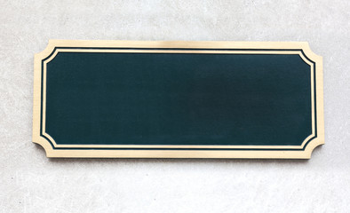 Wall Mural - Empty rectangular green sign with shiny metal border mounted to gray grey stone wall. Copy space.